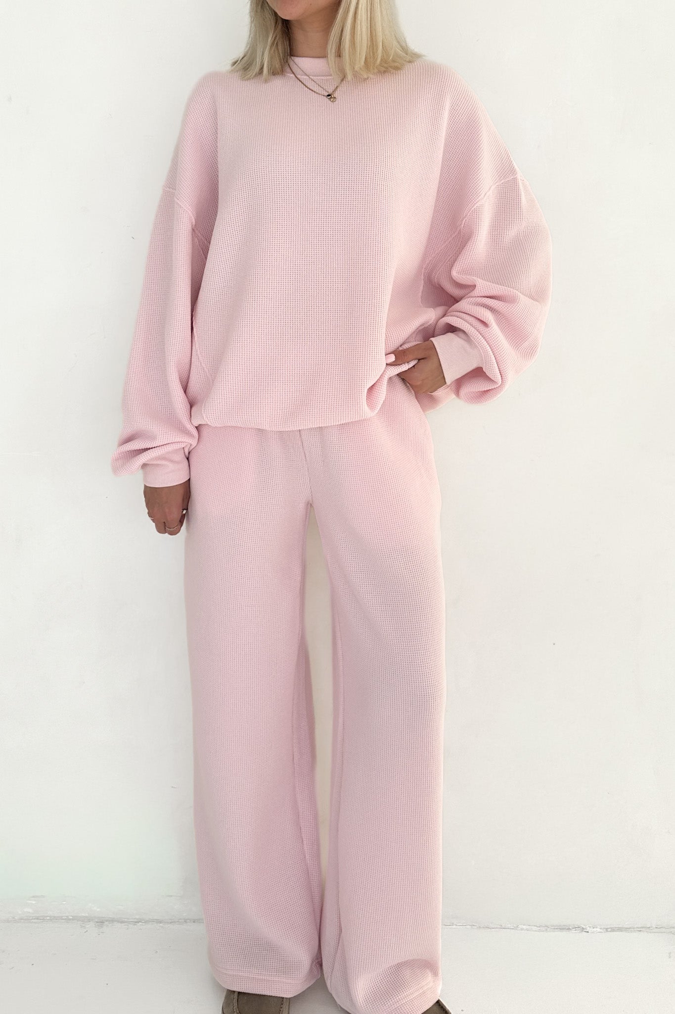 Person wearing a pink tracksuit against a white background
