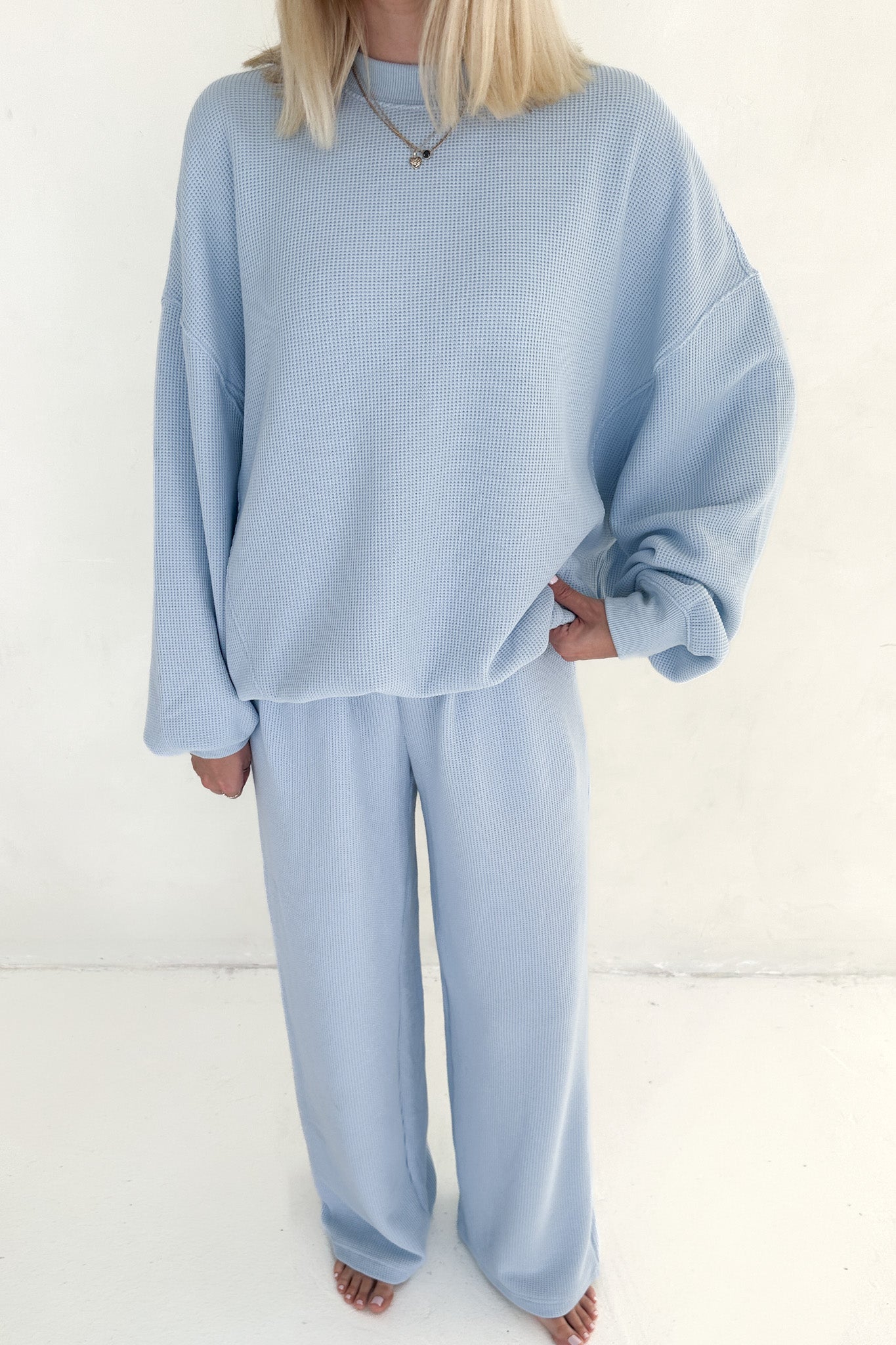 Person wearing a light blue outfit on a white background