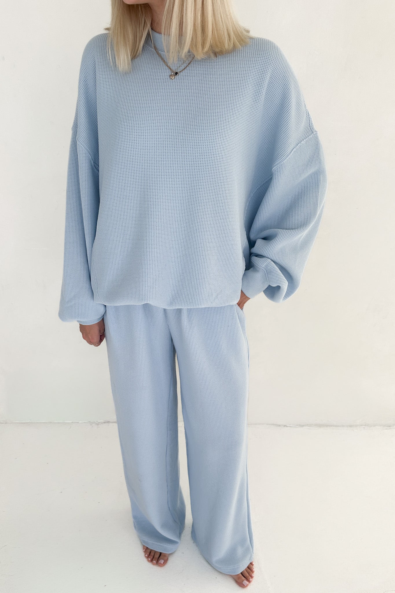 Person wearing a light blue outfit on a white background