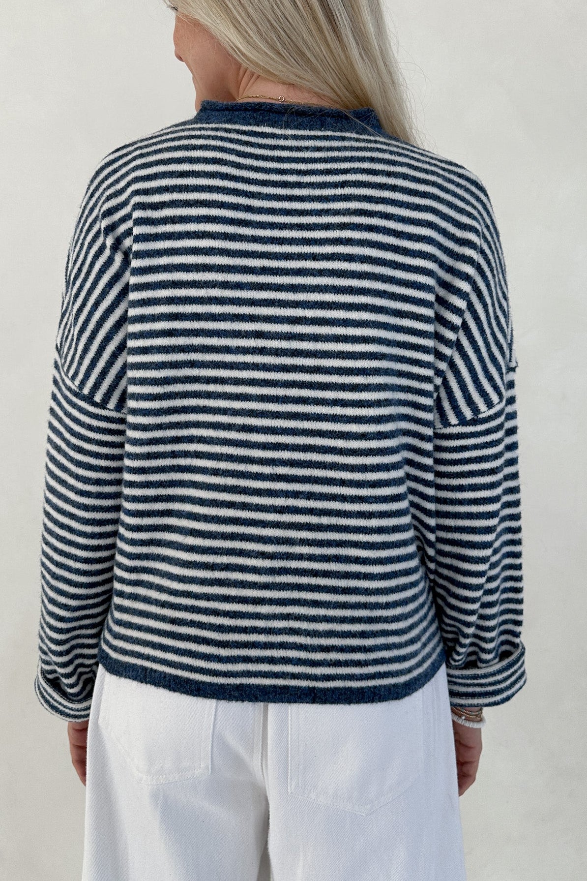 Person wearing a blue and white striped sweater against a plain background