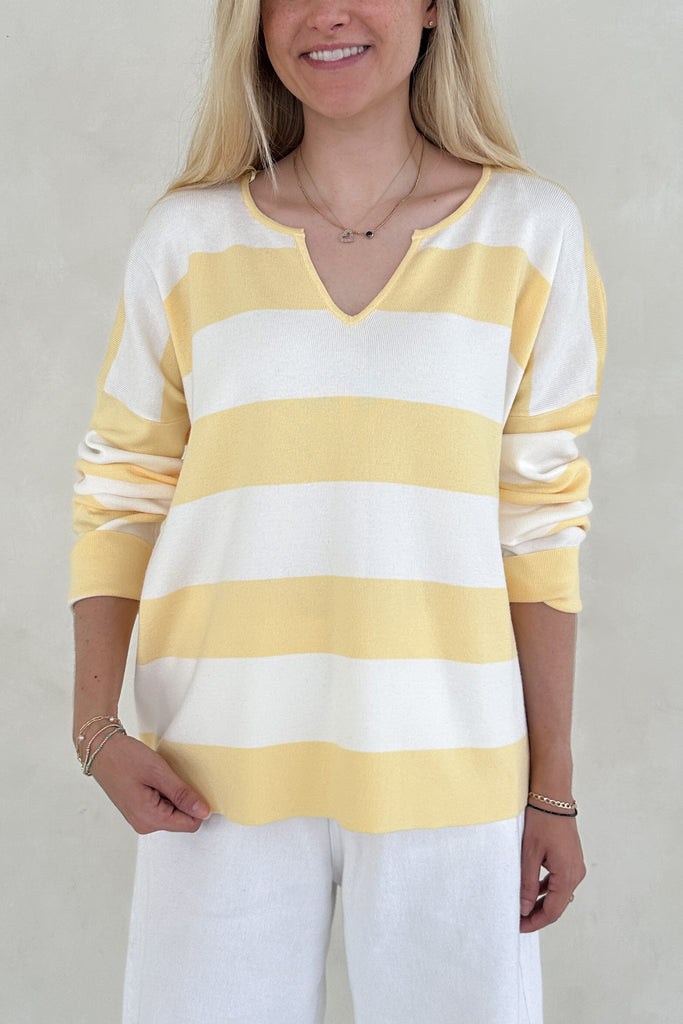 Person wearing a yellow and white striped sweater against a plain background