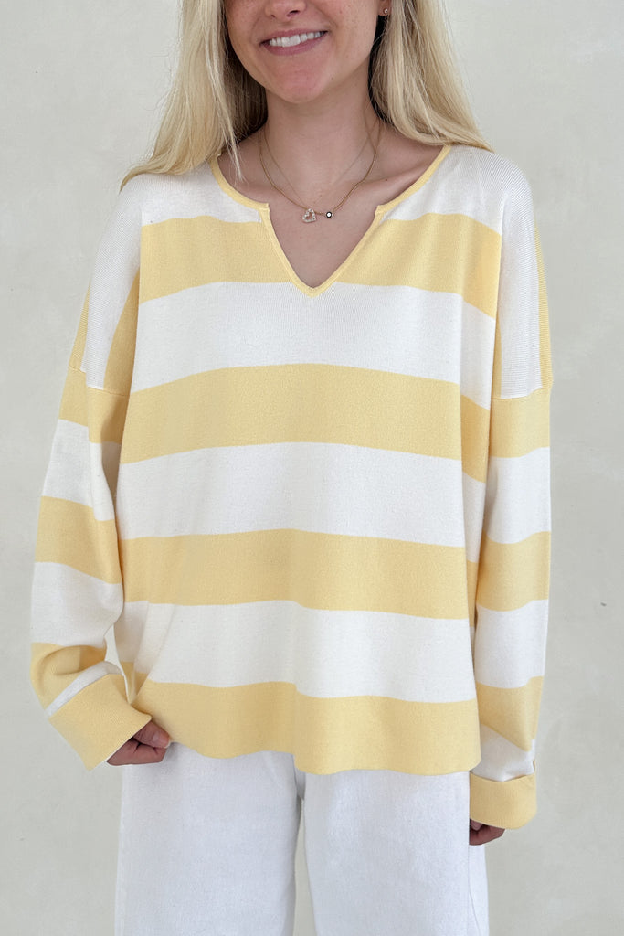 Woman wearing a yellow and white striped sweater against a plain background