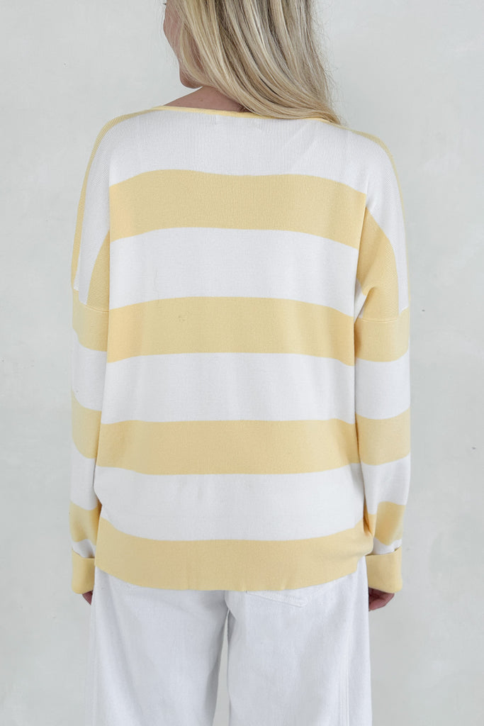 Person wearing a yellow and white striped sweater against a plain background