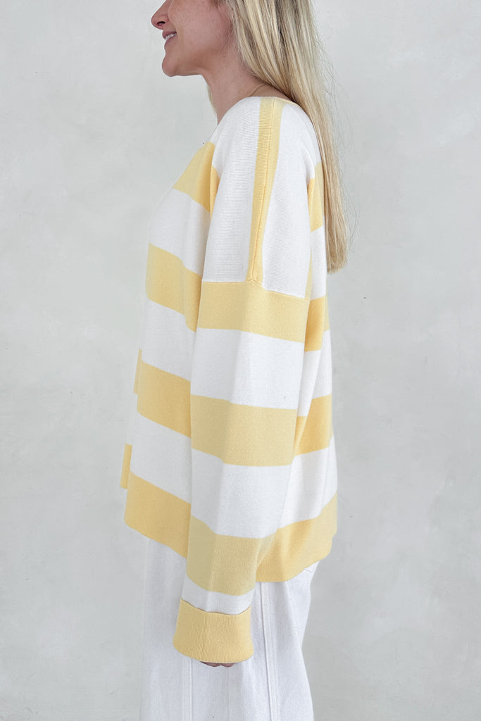 Woman wearing a yellow and white striped shirt against a plain background