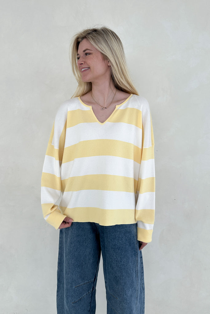 Woman wearing a yellow and white striped sweater against a plain background