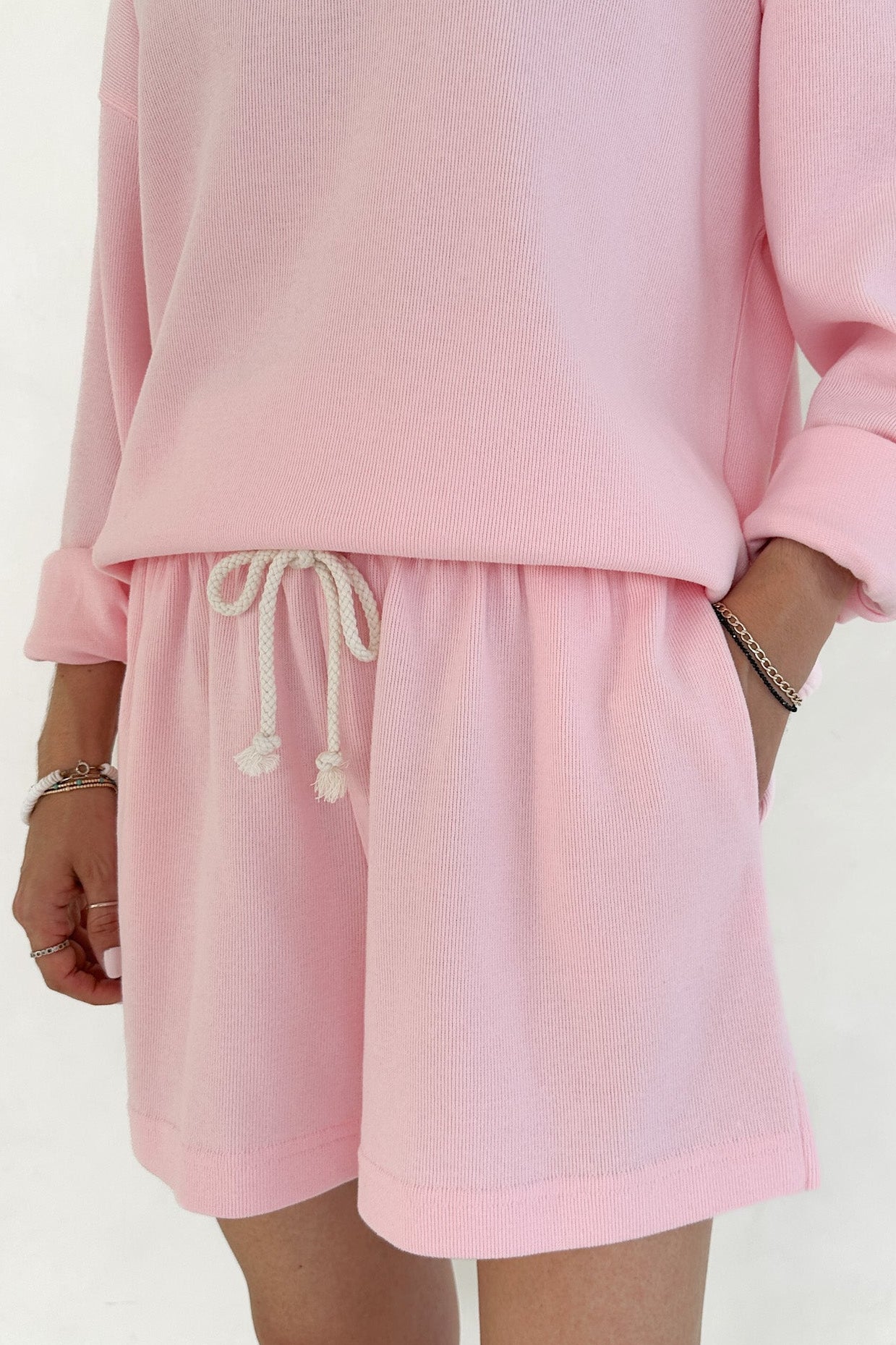 Person wearing a pink outfit with shorts and a top on a white background