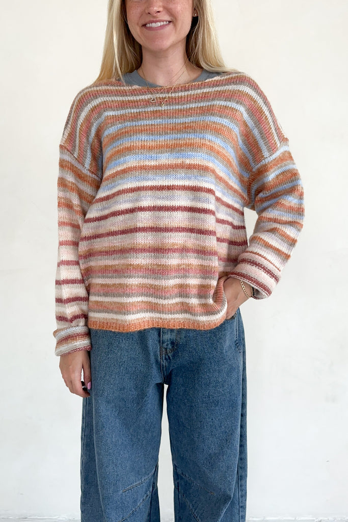 Person wearing a striped sweater and jeans against a white background