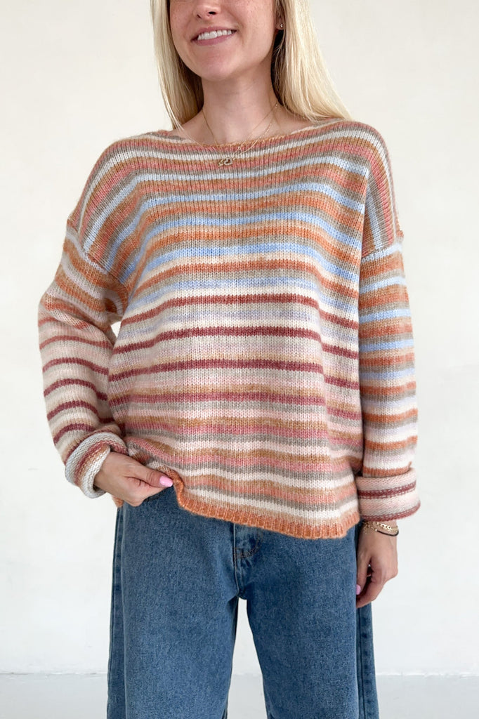 Person wearing a striped sweater and jeans against a white background