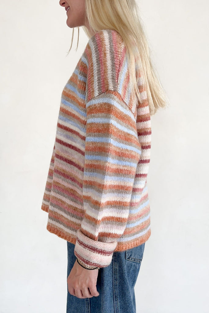 Person wearing a striped sweater with a plain background