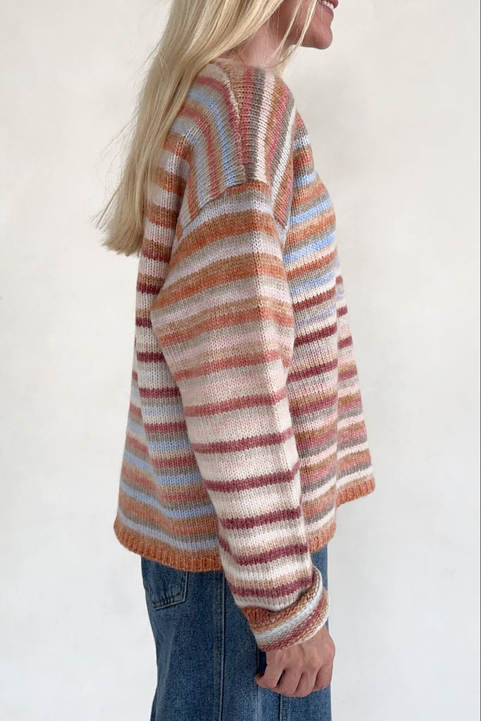 Person wearing a striped sweater with a plain background