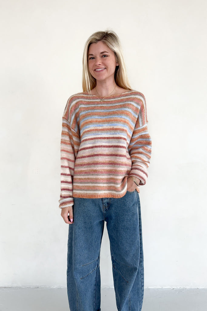 Woman wearing a striped sweater and jeans against a white background