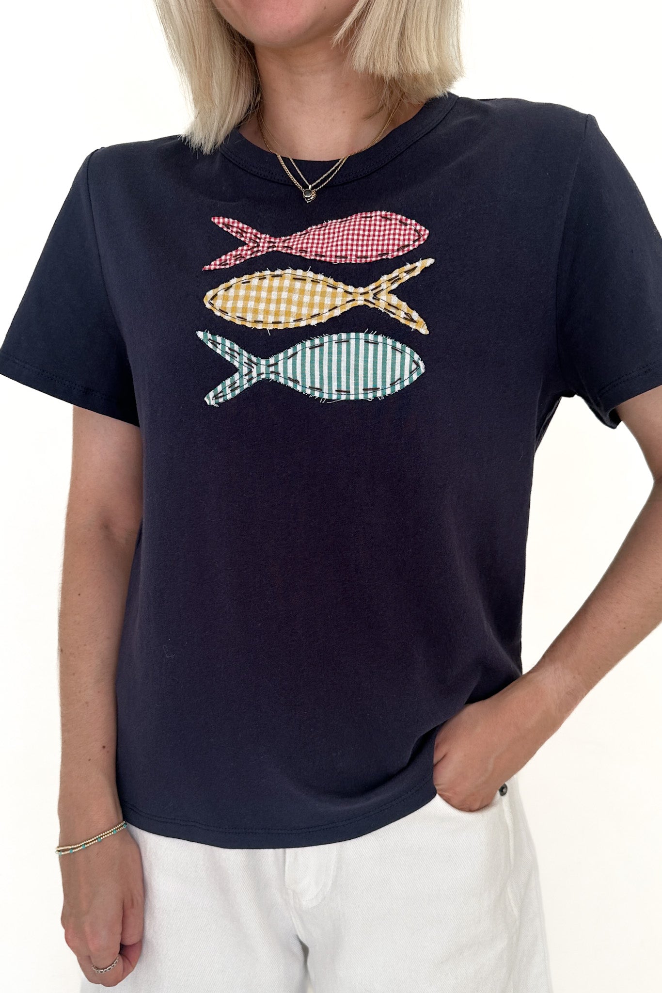 Navy blue t-shirt with colorful fish graphic worn by a person on a white background