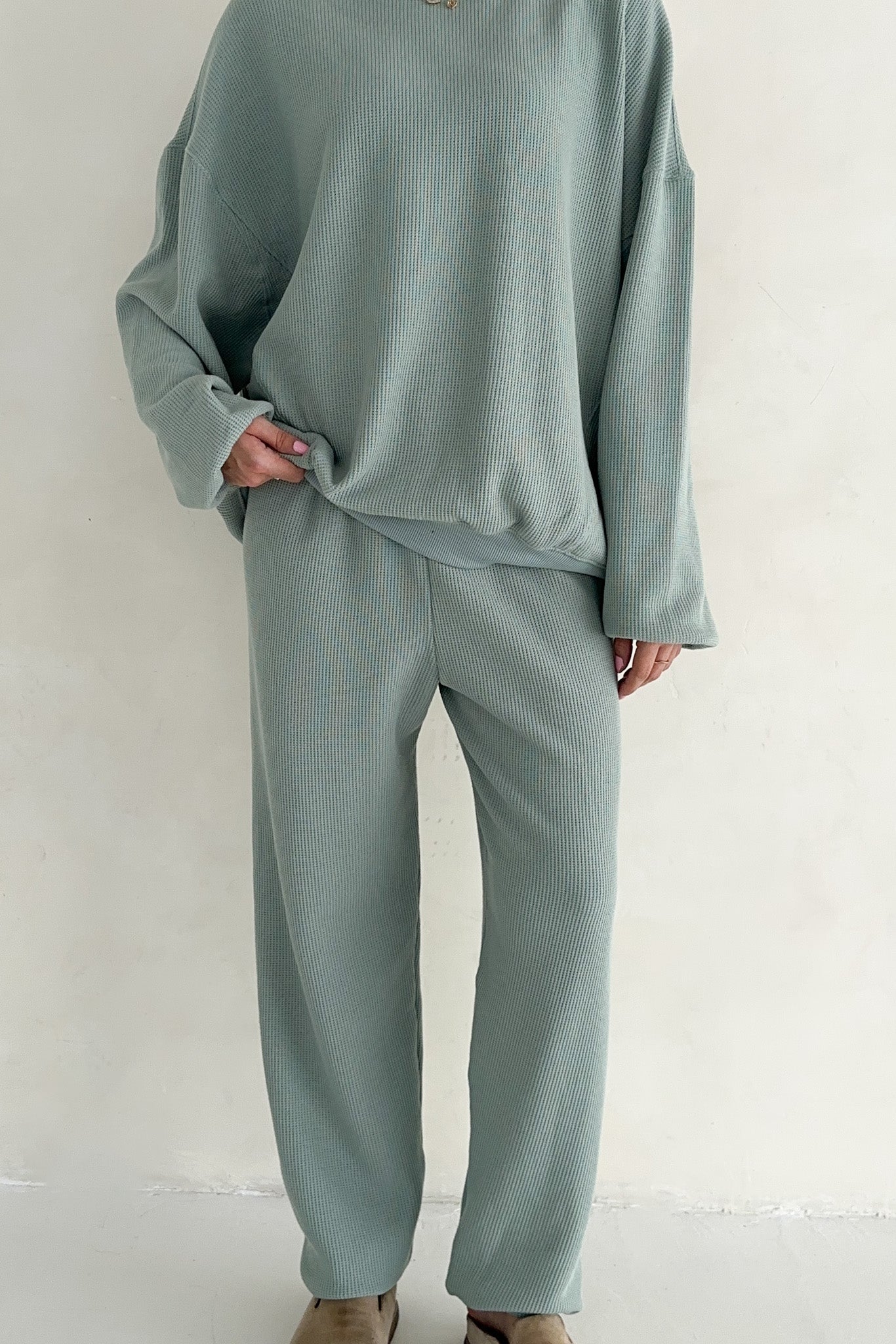 Person wearing a light green outfit against a plain background