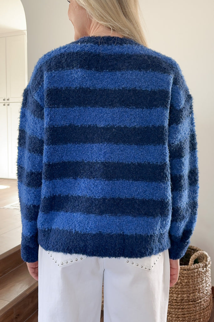 Person wearing a blue striped sweater in an indoor setting