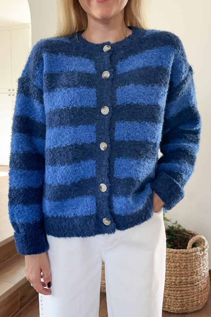 Person wearing a blue striped cardigan with a neutral background