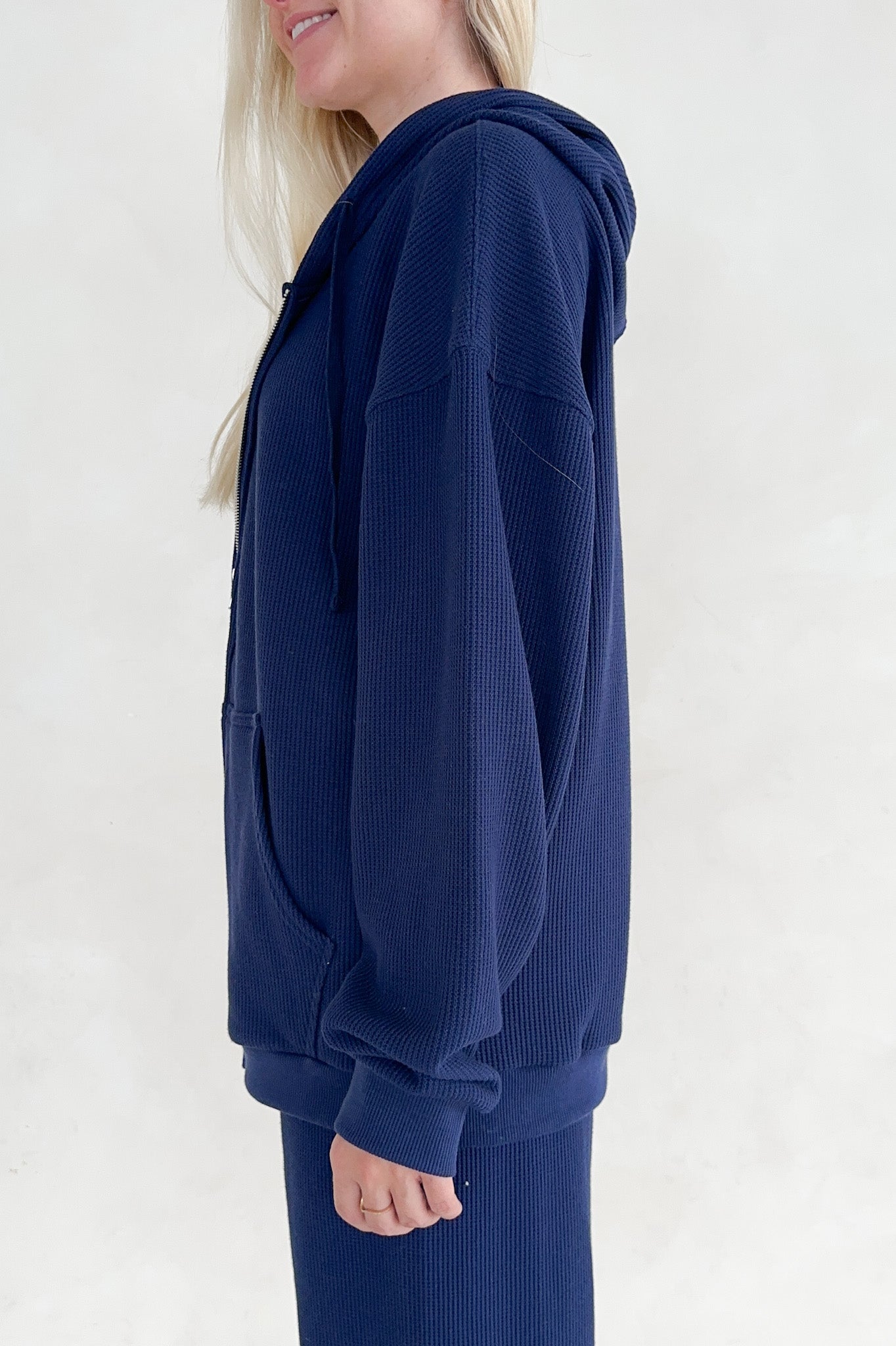 Person wearing a navy blue hoodie on a white background