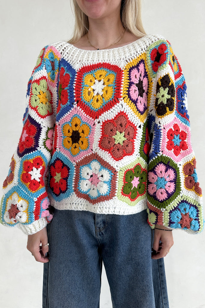 Person wearing a colorful crochet sweater with a white background