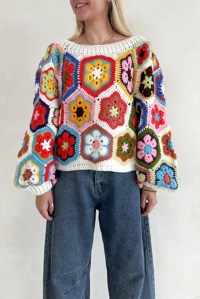 Person wearing a colorful crochet sweater with a white background