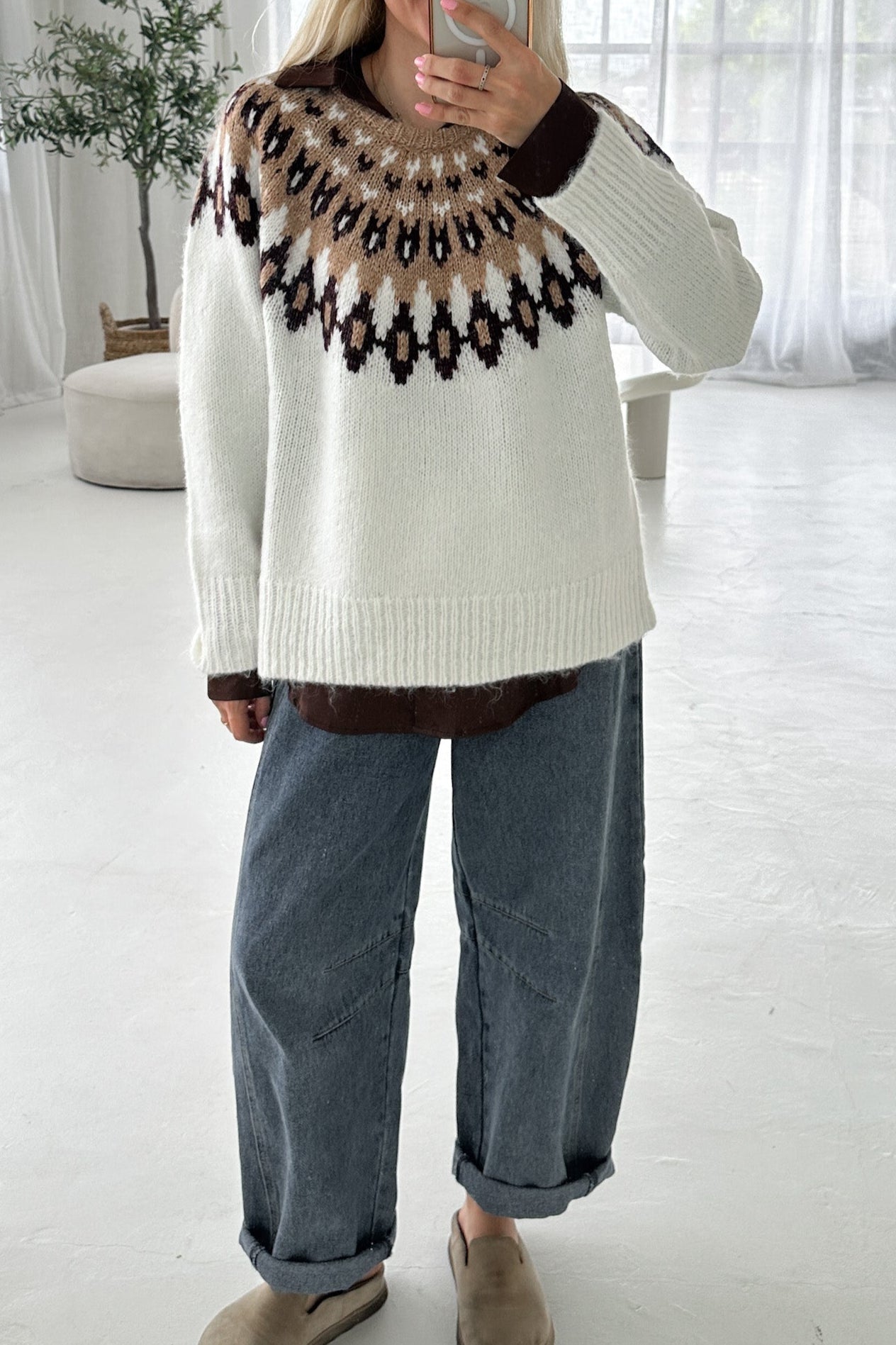 Person wearing a patterned sweater with a neutral background