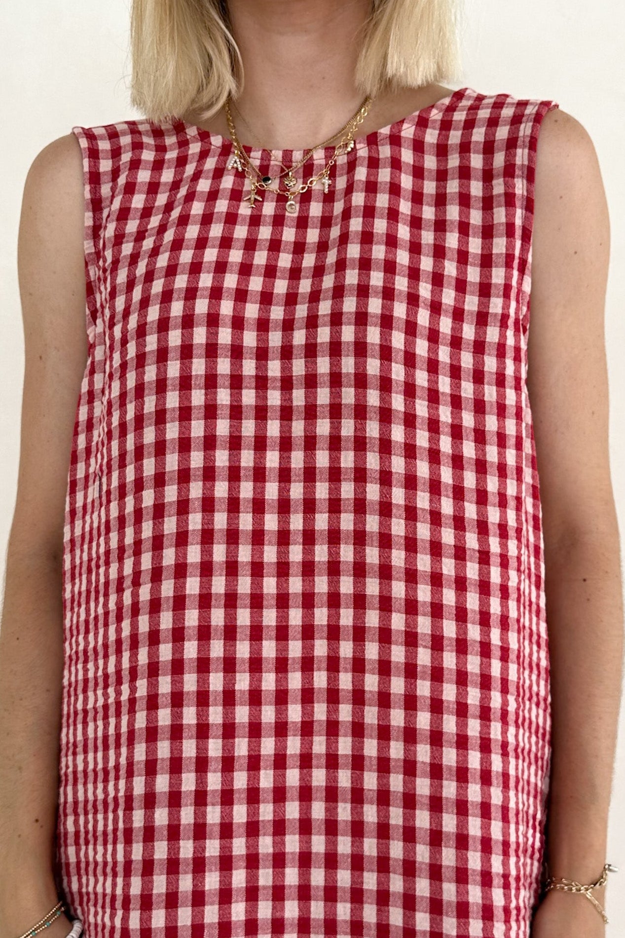 Red and white checkered dress worn by a person on a plain background