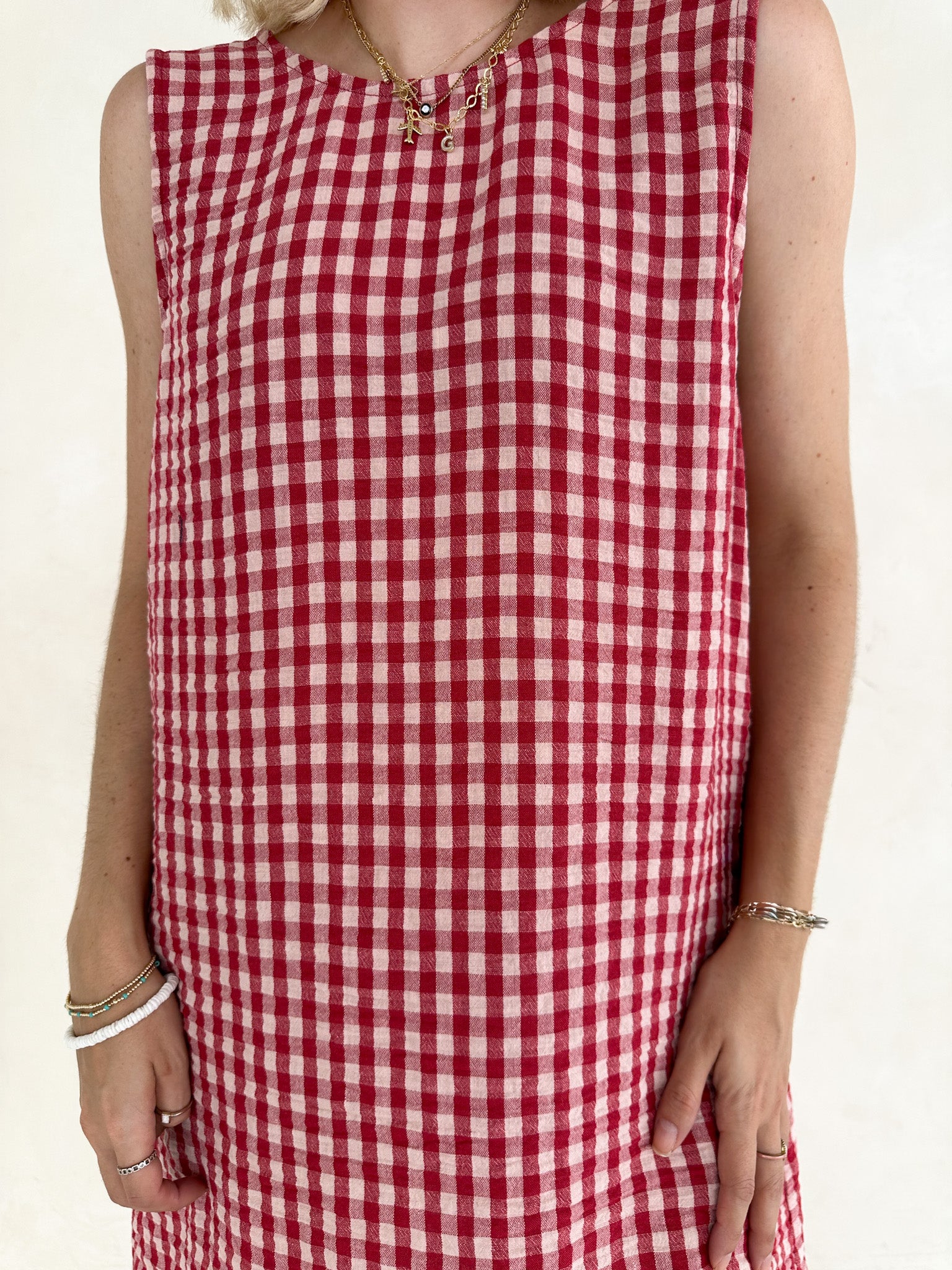 Red and white checkered dress worn by a person on a beige background