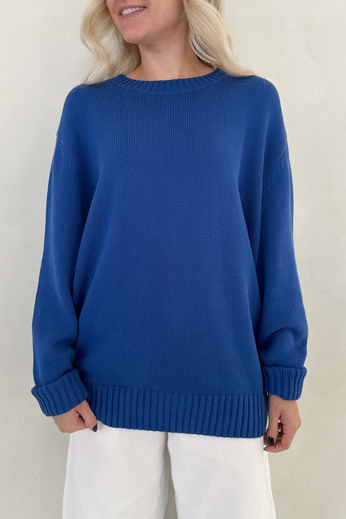 Person wearing a blue sweater against a beige background