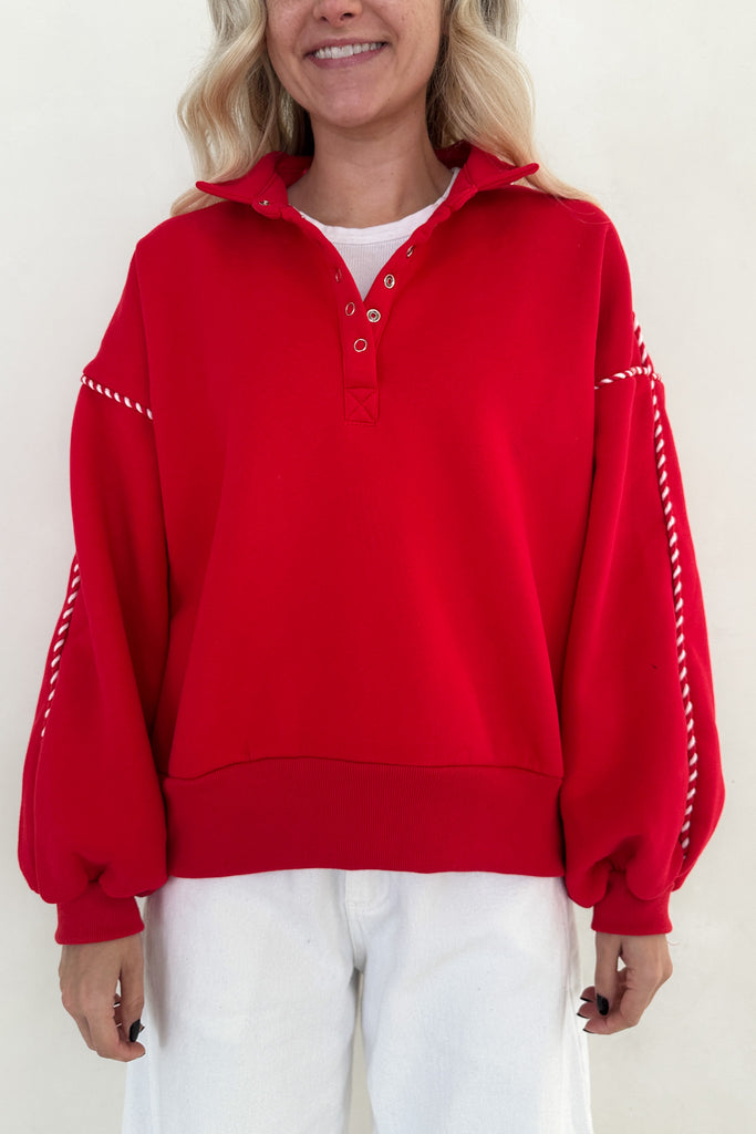 Person wearing a red sweater with white accents on a plain background