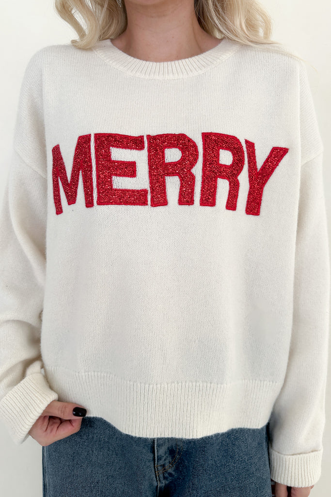 White sweater with red 'MERRY' text worn by a person