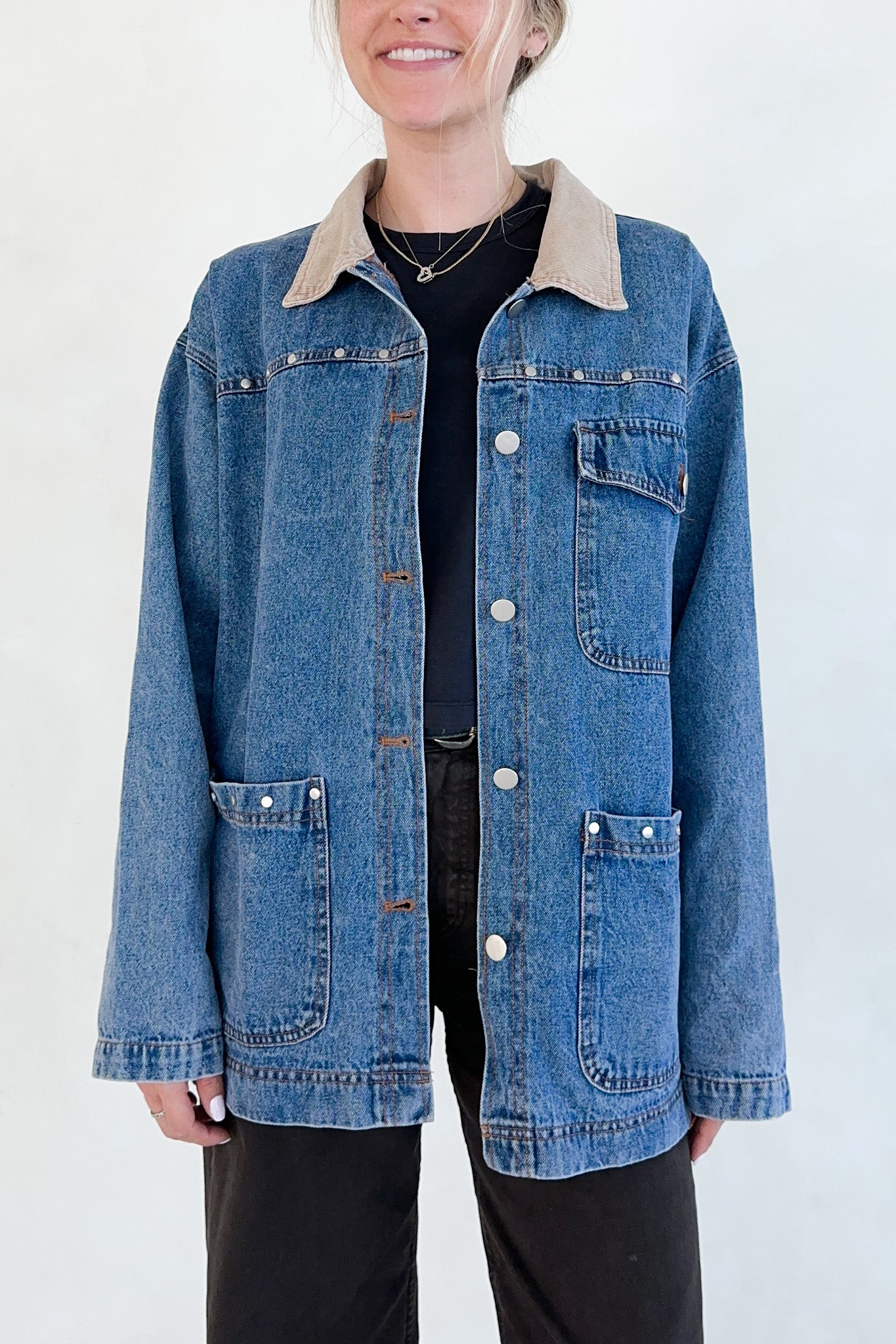 Person wearing a blue denim jacket with beige collar against a white background