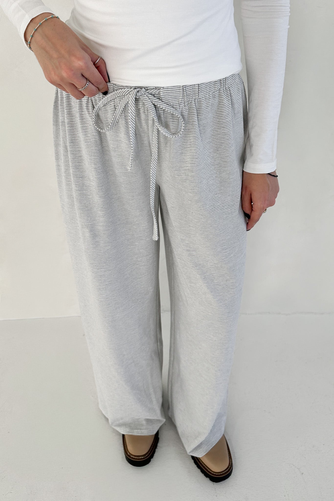 Person wearing gray checkered pants with a white top on a white background