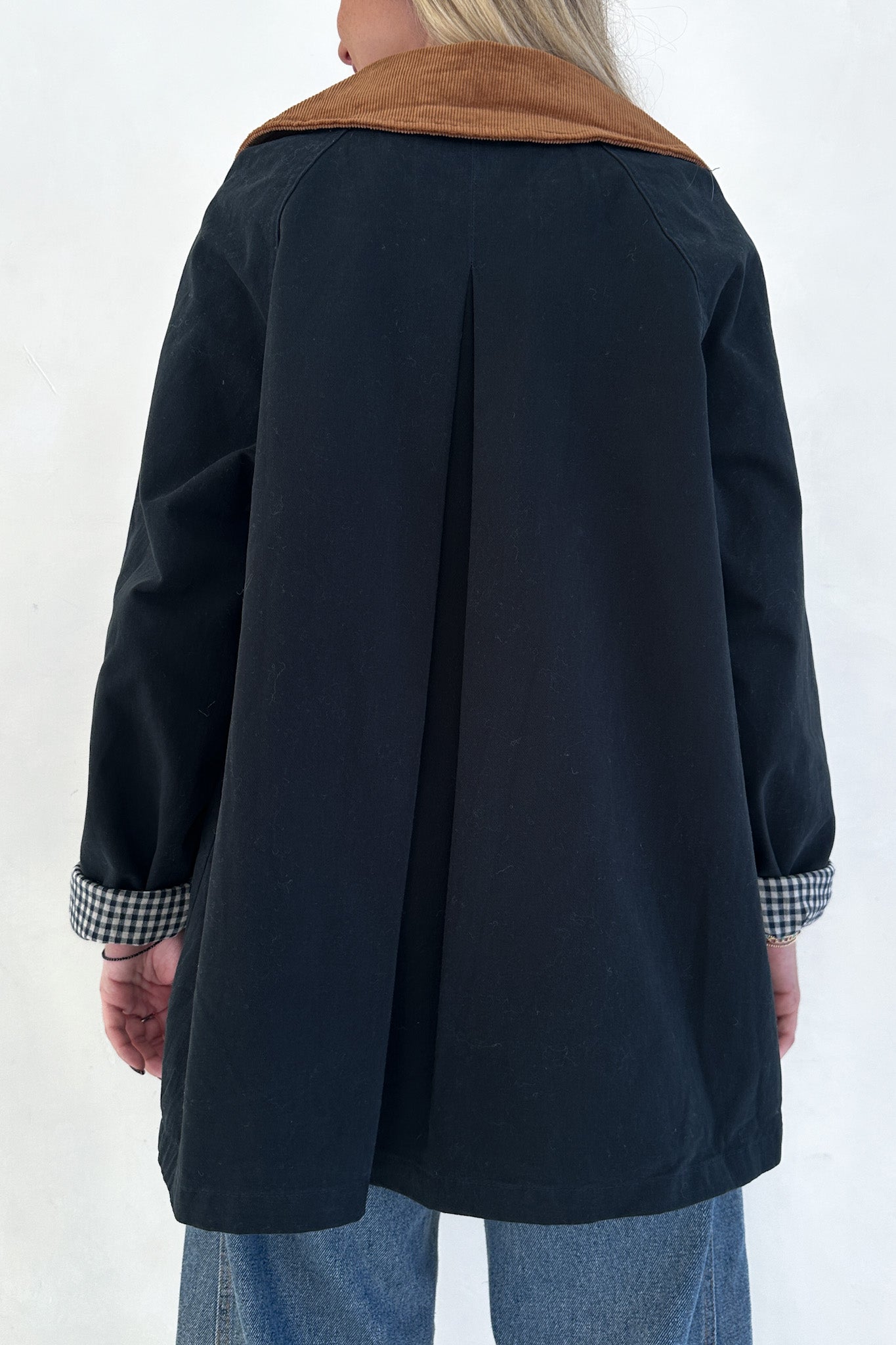 Person wearing a navy coat with a brown collar against a white background