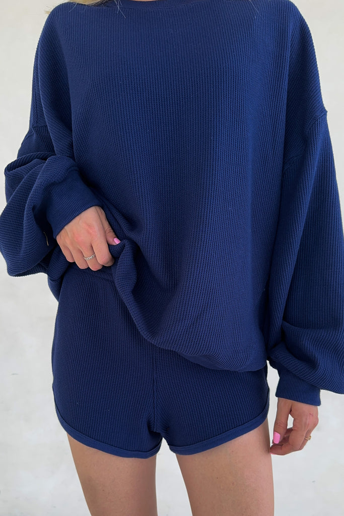 Person wearing a blue sweatshirt and shorts set on a white background