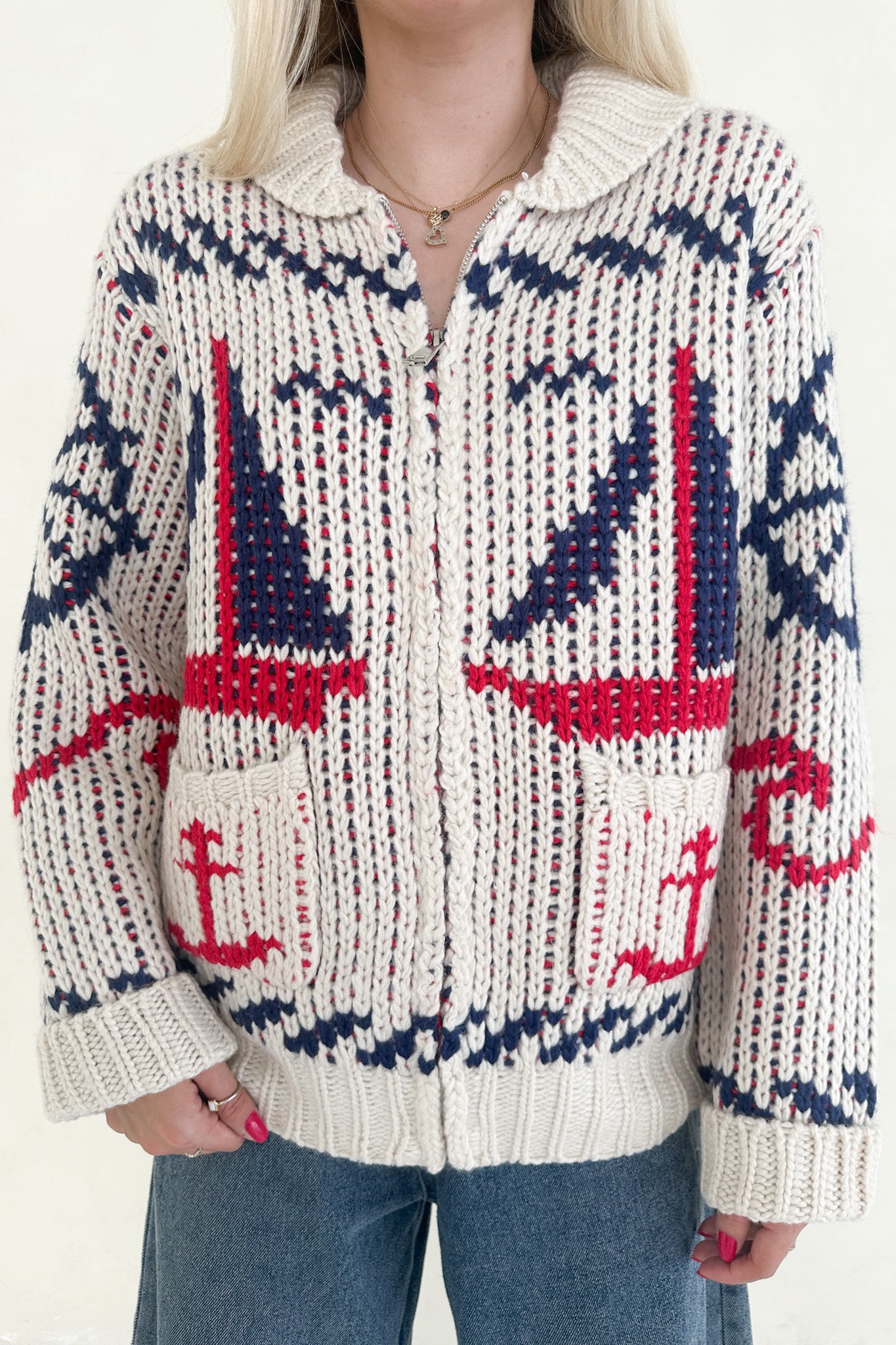 Person wearing a knitted sweater with red and blue patterns on a white background