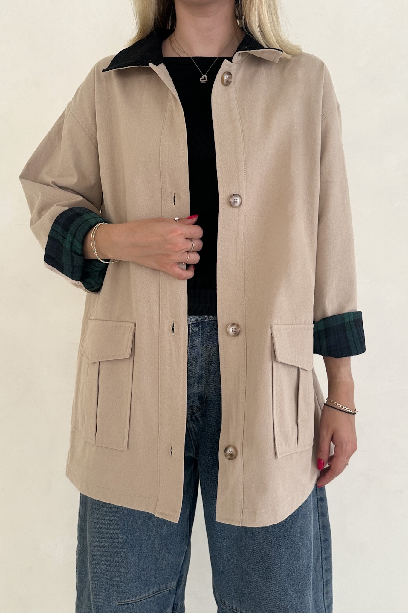 Beige jacket with black accents worn by a person on a white background