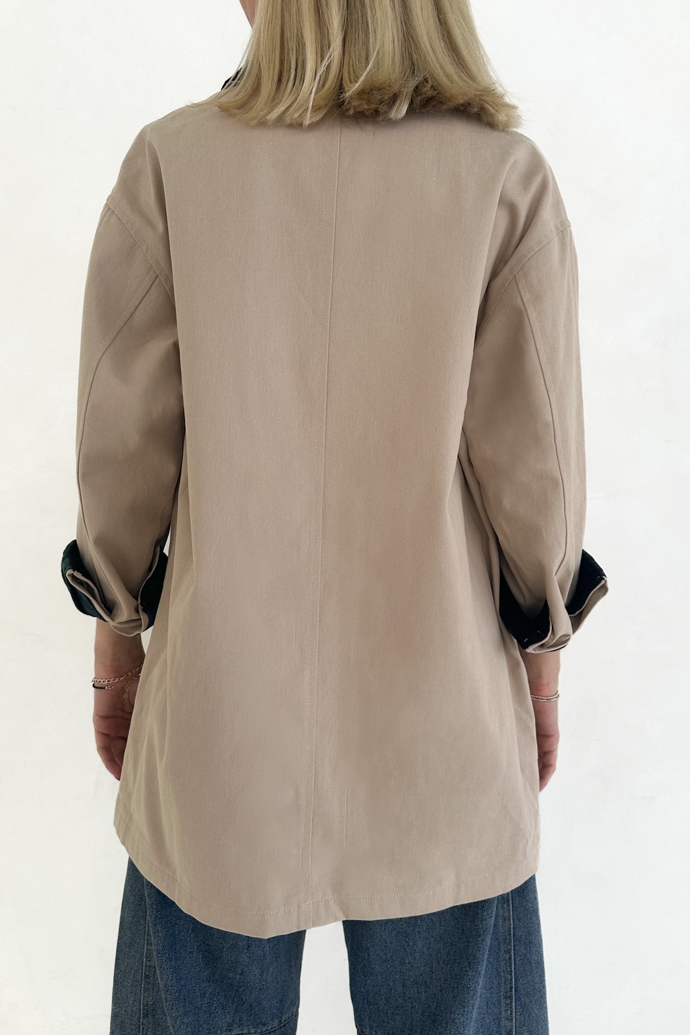 Beige jacket worn by a person on a white background