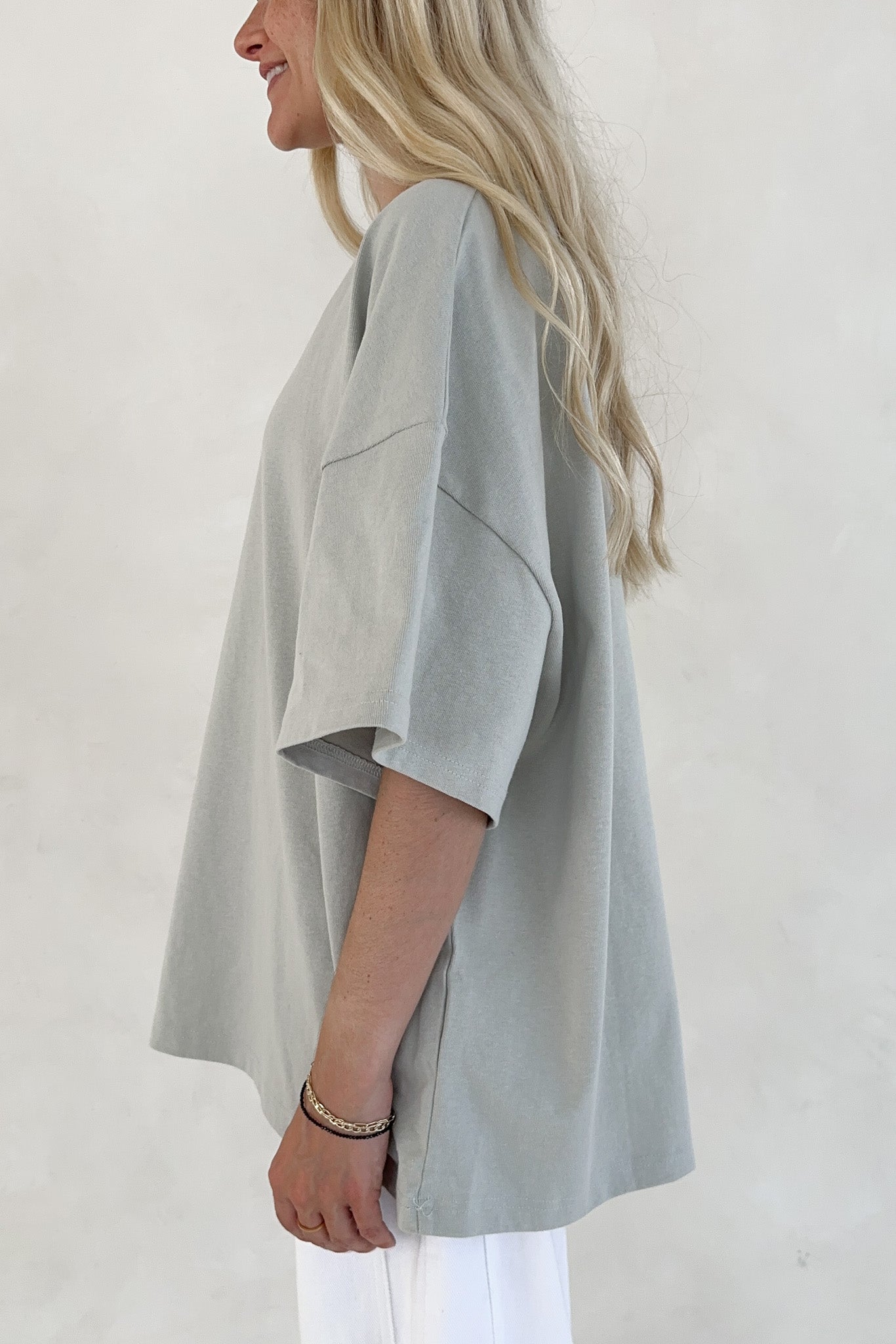 Person wearing a light sage oversized shirt with a plain background