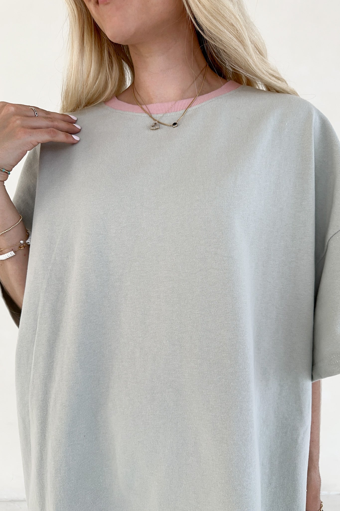 Woman wearing a light sage oversized shirt with a blurred background