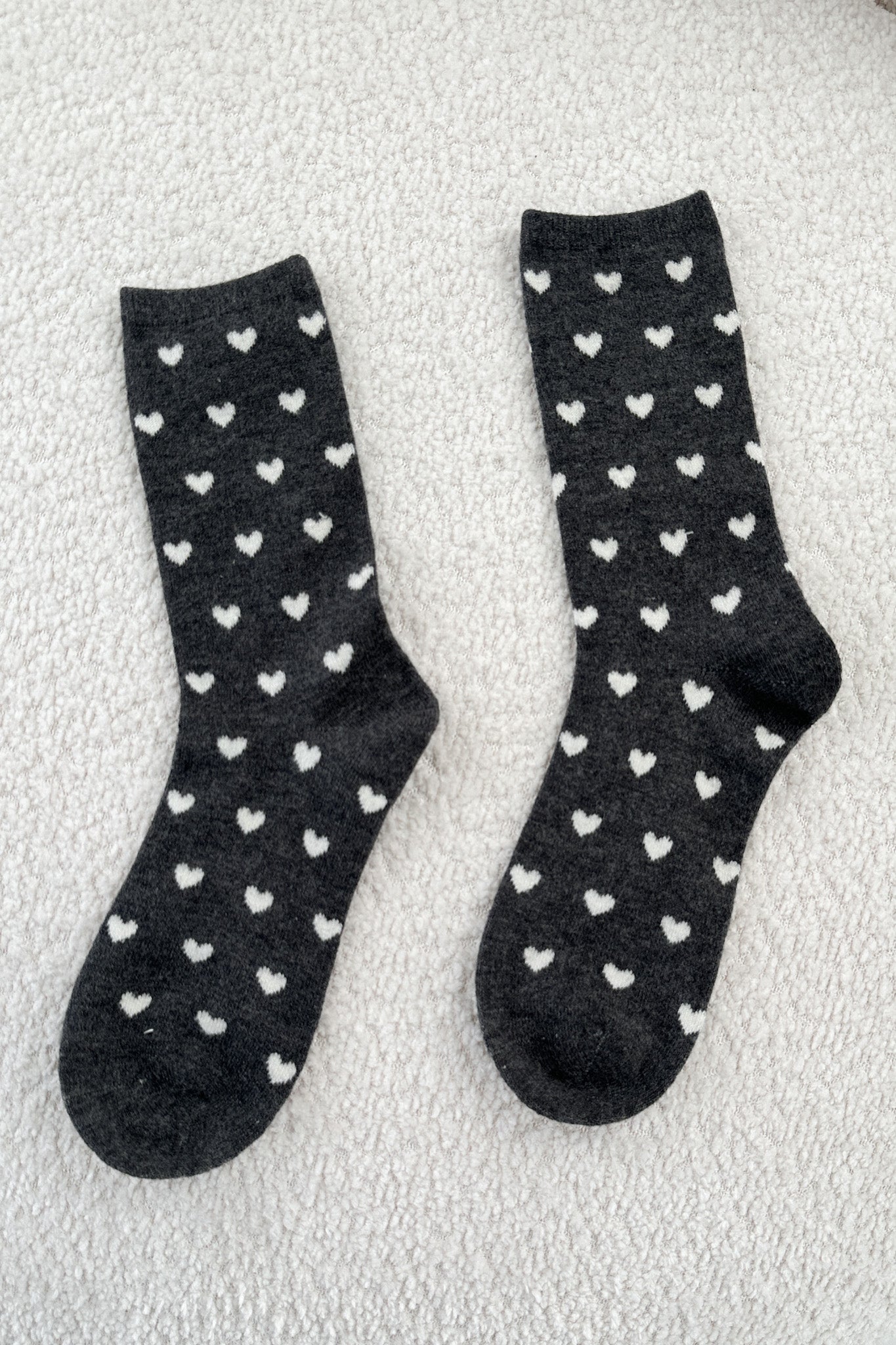 Black socks with white heart patterns on a textured surface