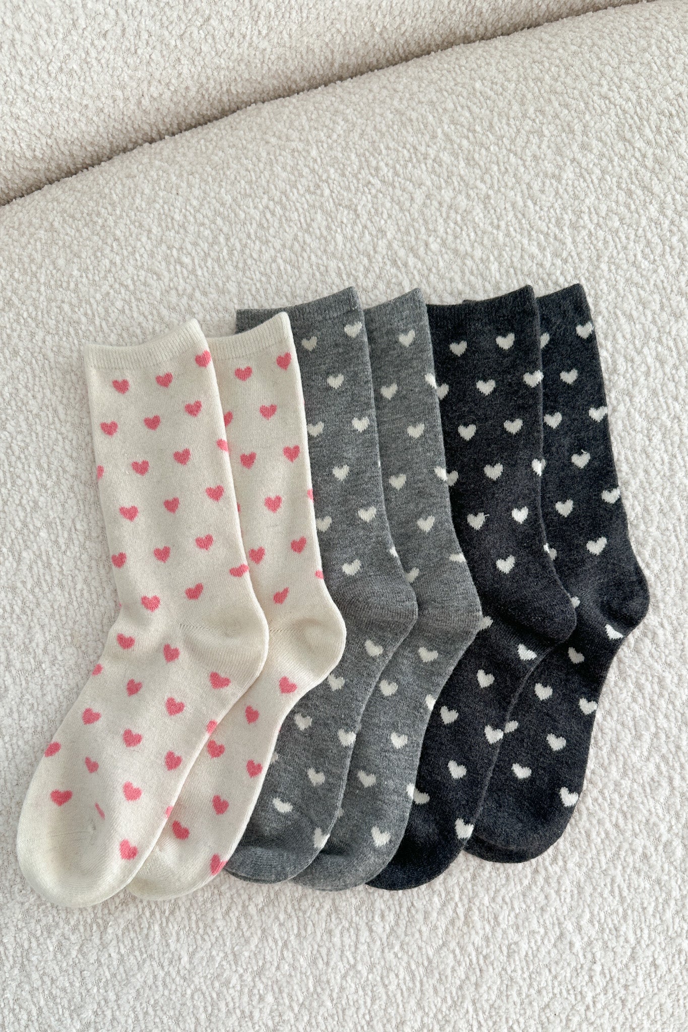 Set of four pairs of socks with heart patterns on a light background