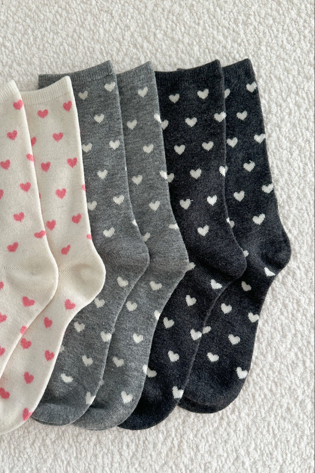 Set of four pairs of socks with heart patterns on a light background