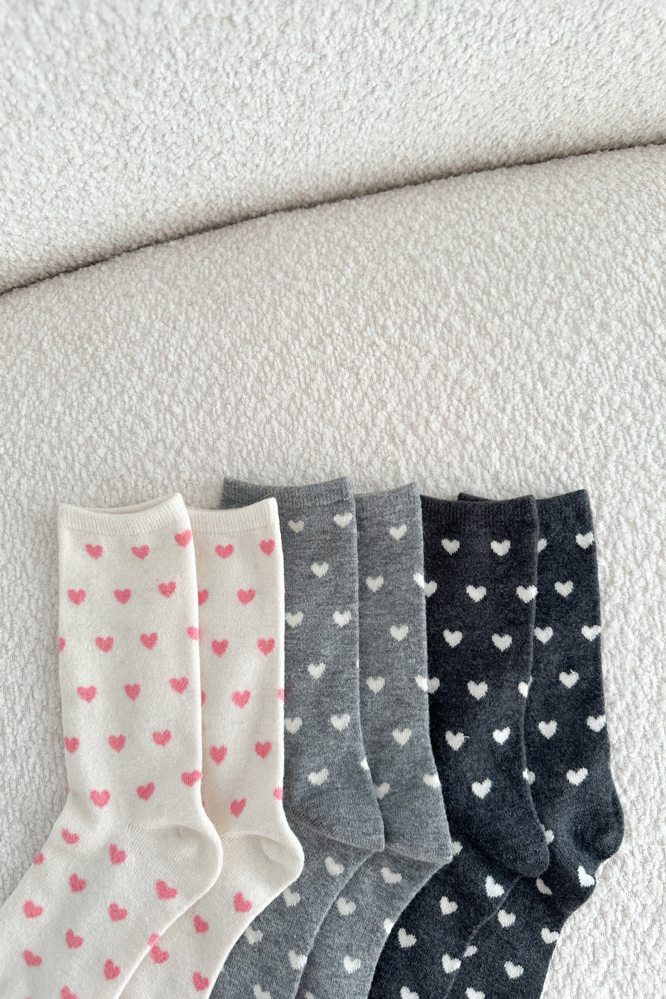 Set of three pairs of socks with heart patterns on a textured surface