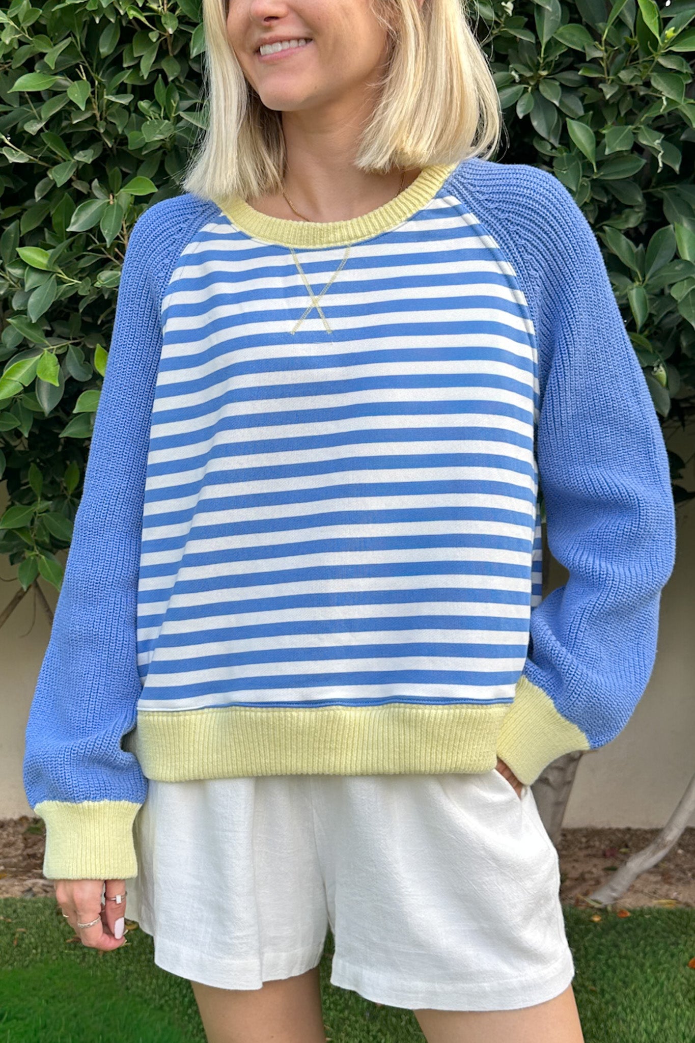 Person wearing a blue and white striped sweater with yellow accents outdoors.