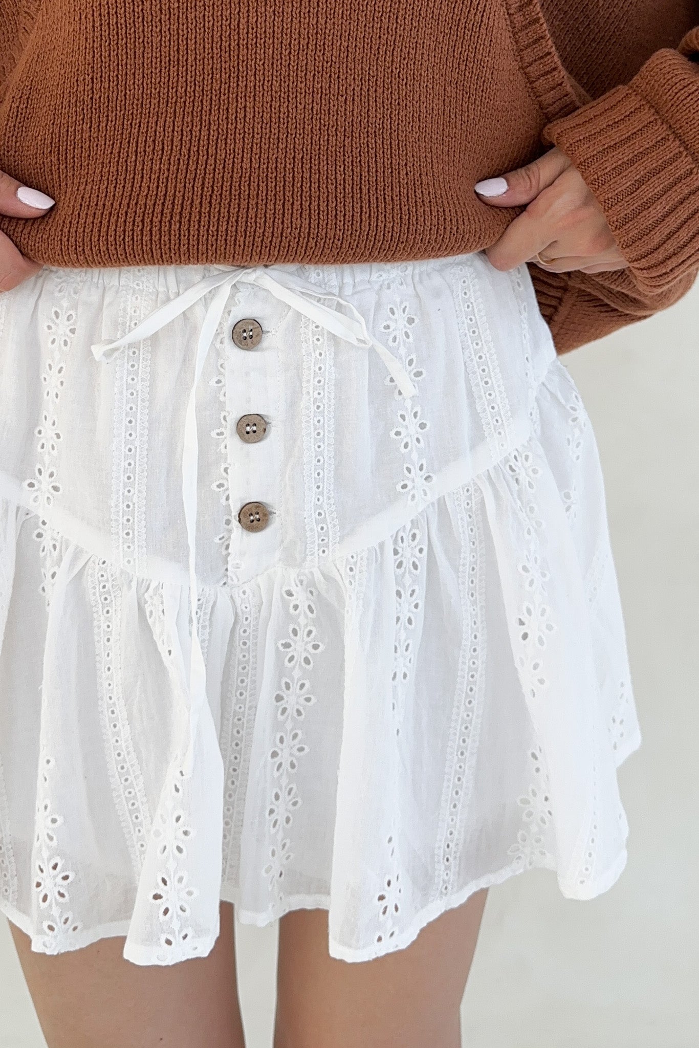 Person wearing a beige knitted cardigan against a white background